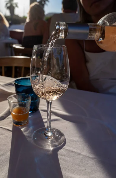 Dinner at sunset in French gourmet restaurant with cold dry rose wine in Port Grimaud, summer vacation on French Riviera, France