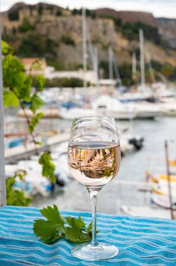 Açık terasta sunulan Rose Provencal şarabı Cassis, Provence, Fransa 'daki eski balıkçıların limanında renkli teknelerle servis ediliyor.