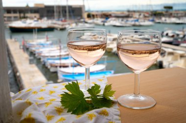 Açık terasta sunulan Rose Provencal şarabı Cassis, Provence, Fransa 'da renkli tekneleri olan eski balıkçıların limanına bakıyor.