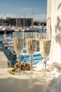 Üç bardak Fransız şampanyası köpüklü şarap ve renkli balıkçı teknelerinin manzarası Cassis, Provence, Fransa 'daki eski limanda, yaz partisinde