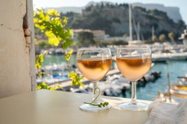 Soğuk gül Provencal şarabı bardaklarla sunuluyor. Açık terasta sunuluyor. Eski balıkçıların limanında, Cassis, Provence, Fransa 'da renkli tekneleri var.