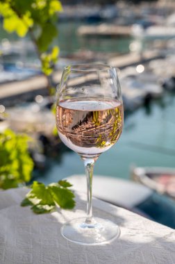 Açık terasta sunulan Rose Provencal şarabı Cassis, Provence, Fransa 'daki eski balıkçıların limanında renkli teknelerle servis ediliyor.