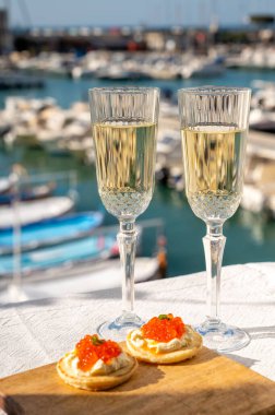 Ekşi krema ve tuzlu somon kırmızısı havyar ve Fransız şampanyası brut köpüklü şarap ile küçük krep çiftleri Cassis, Provence, Fransa 'nın limanındaki renkli teknelerde servis edilir.