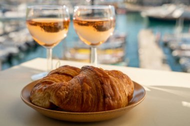 Provence 'de yaz mevsimi, taze kruvasanlar ve gül şarabı bardakları Cassis, Provence, Fransa' da tatil yapan balıkçıların teknelerinin manzarası.