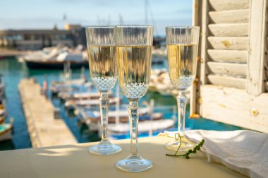 Üç bardak Fransız şampanyası köpüklü şarap ve renkli balıkçı teknelerinin manzarası Cassis, Provence, Fransa 'daki eski limanda, yaz partisinde