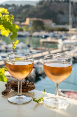 Soğuk gül Provencal şarabı bardaklarla sunuluyor. Açık terasta sunuluyor. Eski balıkçıların limanında, Cassis, Provence, Fransa 'da renkli tekneleri var.