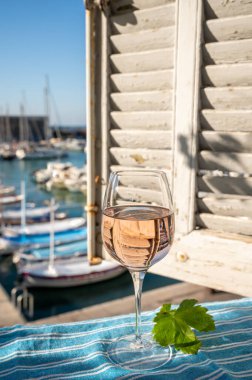 Açık terasta sunulan Rose Provencal şarabı Cassis, Provence, Fransa 'daki eski balıkçıların limanında renkli teknelerle servis ediliyor.