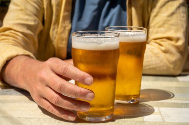 Güneşli yaz gününde Fransız açık hava kafesinde iki bardak taze soğuk bira içen adamlar.