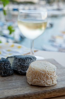 Fransız beyaz ve siyah keçi peyniri crottin ve bir bardak beyaz Fransız şarabı Cassis, Provence, Fransa limanındaki teknelerde servis edilir.