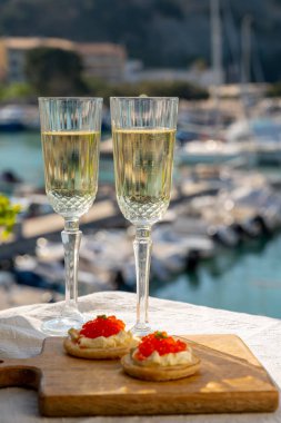 Ekşi krema ve tuzlu somon kırmızısı havyar ve Fransız şampanyası brut köpüklü şarap ile küçük krep çiftleri Cassis, Provence, Fransa 'nın limanındaki renkli teknelerde servis edilir.