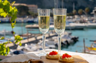 Ekşi krema ve tuzlu somon kırmızısı havyar ve Fransız şampanyası brut köpüklü şarap ile küçük krep çiftleri Cassis, Provence, Fransa 'nın limanındaki renkli teknelerde servis edilir.