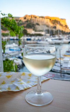 Cassis şarap üretim bölgesinden gelen soğuk beyaz şarap, Fransa, Provence, Cassis 'te renkli tekneleri olan eski balıkçıların limanına bakan terastaki camlarda servis edilir.