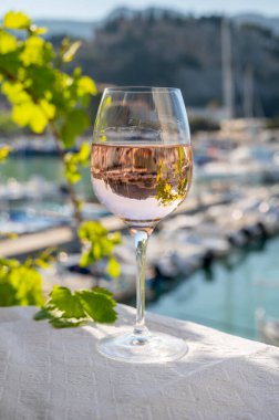 Açık terasta sunulan Rose Provencal şarabı Cassis, Provence, Fransa 'daki eski balıkçıların limanında renkli teknelerle servis ediliyor.