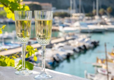 İki bardak Fransız şampanyası, köpüklü şarap ve renkli balıkçı teknesiyle Cassis, Provence, Fransa 'daki eski limanda öğle yemeği.