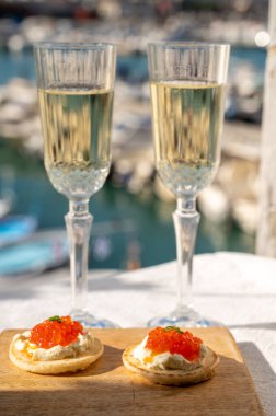 Ekşi krema ve tuzlu somon kırmızısı havyar ve Fransız şampanyası brut köpüklü şarap ile küçük krep çiftleri Cassis, Provence, Fransa 'nın limanındaki renkli teknelerde servis edilir.
