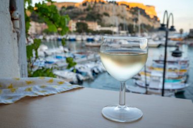 Cassis şarap üretim bölgesinden gelen soğuk beyaz şarap, Fransa, Provence, Cassis 'te renkli tekneleri olan eski balıkçıların limanına bakan terastaki camlarda servis edilir.