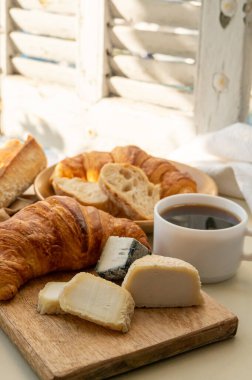 Fransız kahvaltısında taze kruvasan, baquett ekmeği, crottin keçi peyniri, sade kahve ve Cassis, Provence, Fransa 'daki balıkçı tekneleri manzaralı. Provence 'de Tatil.