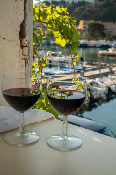 Drinking of red dry wine on outdoor terrace with view on old fisherman\'s harbour with colourful boats in Cassis, Provence, France