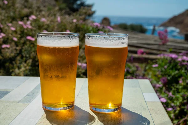 Two glasses of fresh cold lager beer served outdoor in snack bar with view on Calanque de Figuerolles in La Ciotat, Provence, France in sunny day