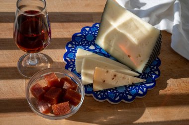 İspanyol sert manchegosu, inek, koyun ve keçi peyniri açık havada membrillo reçeli ve bir bardak şeri şarabı ile servis edilir. Mavi Endülüs stil panosunda. Kapatın.