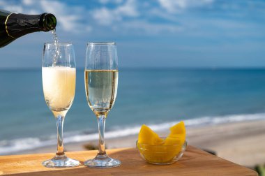 Güneşli bir günde İspanyol Cava şarabı, ananas ve mavi deniz manzaralı açık hava kahvaltısı ve Marbella 'da kumlu plaj, Costa del Sol tatil beldesi, Endülüs, İspanya