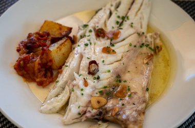 Eski kömür parillası üzerinde sarımsak ve zeytinyağıyla ızgara edilmiş taze balık lokantasında küçük balıkçı köyü Getaria 'da beyaz levrek balığı yemek.