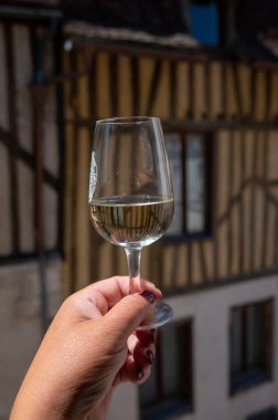 Tasting of white grand cru classe chablis wine with old French houses on background, Burgundy, wine tour is France