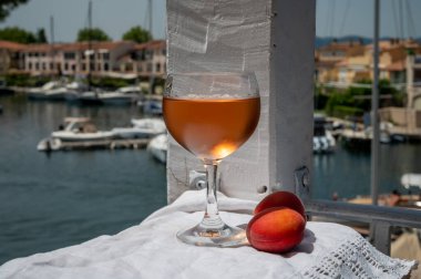 Drinking of cold rose wine from Provence with red apricots and view on yacht harbour of Port Grimaud, summer vacation on French Riviera, France