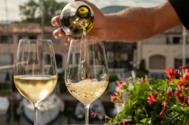 Port Grimaud limanında bir yat limanında soğuk beyaz şarap bardakları doldurmak, Fransa 'nın Provence şehrinde Fransız Riviera' sında yaz tatili