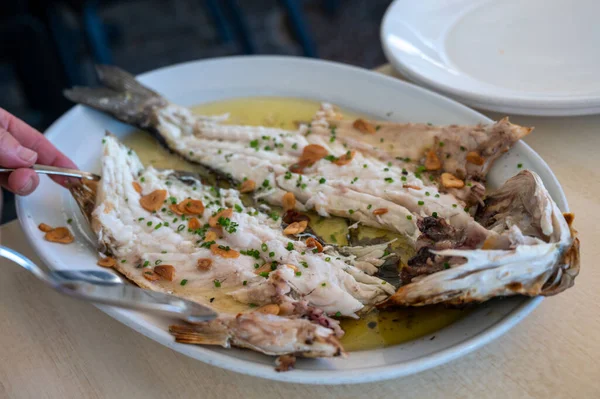 スペイン バスク州ゲタリアの小さな漁師の村で古い木炭パルリラの海の低音魚にニンニクとオリーブオイルで焼きたてのレストランで提供しています — ストック写真