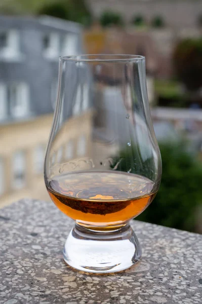 Dram of scotch whiskey with view on old houses on background, Edinburgh whisky tasting tour, Scotland