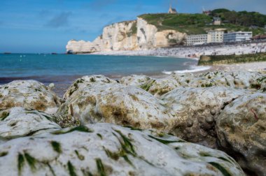 Alçak gelgit dönemi ve okyanusun dibindeki beyaz taşların manzarası ve Fransa 'nın Normandiya eyaletindeki Porte d' Aval kemerinin tebeşir kayalıkları. Turistler için tatil yeri.