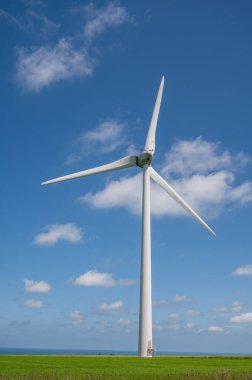 Tarımsal bölgedeki modern rüzgar değirmenleri, yeşil buğday tarlaları ve mavi Atlantik Okyanusu Normandiya, Fransa 'da yaz aylarında Ödenmiştir.