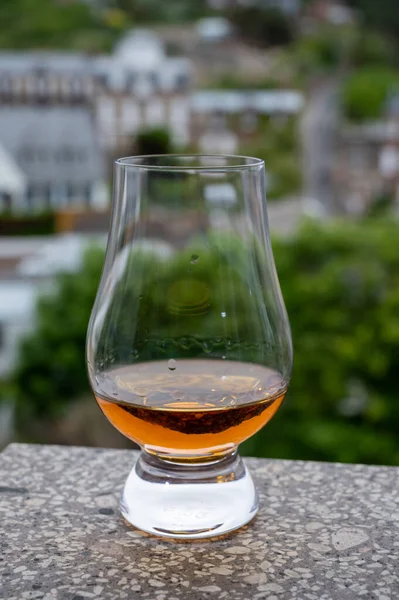 Dram of scotch whiskey with view on old houses on background, Edinburgh whisky tasting tour, Scotland