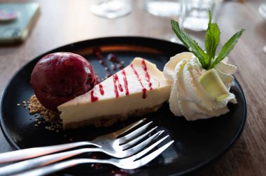 Bir parça peynirli kek, içinde cassis ice, çırpılmış krema ve taze nane şekeri, tatlı tatlılar var.