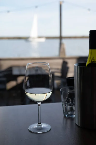 Drinking white dry wine in outdoor cafe-bar with sea view