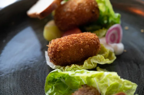 Dutch fast food, deep fried croquettes filled with ground beef meat and served with green salad, close up