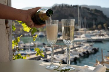 İki bardak Fransız şampanyası, köpüklü şarap ve renkli balıkçıların Cassis, Provence, Fransa 'da eski bir limandaki teknelerine manzarası, Provence' de yaz tatili.