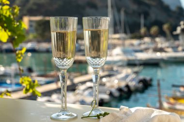 İki bardak Fransız şampanyası, köpüklü şarap ve renkli balıkçıların Cassis, Provence, Fransa 'da eski bir limandaki teknelerine manzarası, Provence' de yaz tatili.