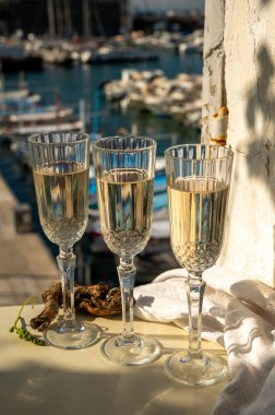 Üç bardak Fransız şampanyası köpüklü şarap ve renkli balıkçı teknelerinin manzarası Cassis, Provence, Fransa 'daki eski limanda, yaz partisinde