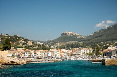 Kumsalda panoramik manzara, mavi deniz, uçurumlar, evler, sokaklar ve bulutlu bir günde Cassis, Provence, Fransa 'da deniz feneriyle eski balıkçıların limanı