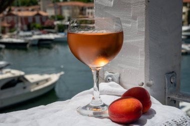 Drinking of cold rose wine from Provence with red apricots and view on yacht harbour of Port Grimaud, summer vacation on French Riviera, France
