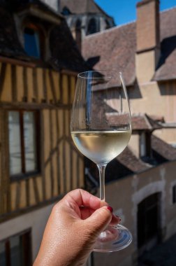 Tasting of white grand cru classe chablis wine with old French houses on background, Burgundy, wine tour is France