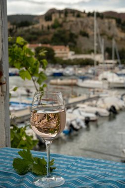 Açık terasta sunulan Rose Provencal şarabı Cassis, Provence, Fransa 'daki eski balıkçıların limanında renkli teknelerle servis ediliyor.