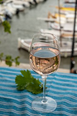 Açık terasta sunulan Rose Provencal şarabı Cassis, Provence, Fransa 'daki eski balıkçıların limanında renkli teknelerle servis ediliyor.