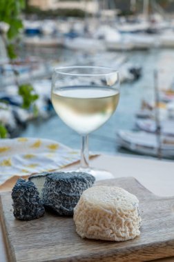 Fransız beyaz ve siyah keçi peyniri crottin ve bir bardak beyaz Fransız şarabı Cassis, Provence, Fransa limanındaki teknelerde servis edilir.