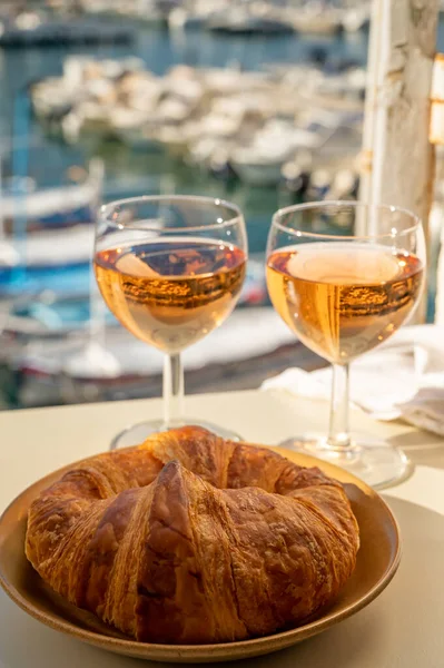 Provence 'de yaz mevsimi, taze kruvasanlar ve gül şarabı bardakları Cassis, Provence, Fransa' da tatil yapan balıkçıların teknelerinin manzarası.