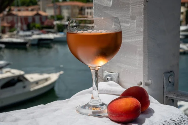 Provence 'den kırmızı kayısılı soğuk gül şarabı içmek ve Port Grimaud limanında yat manzarası, Fransa' nın Riviera şehrinde yaz tatili.