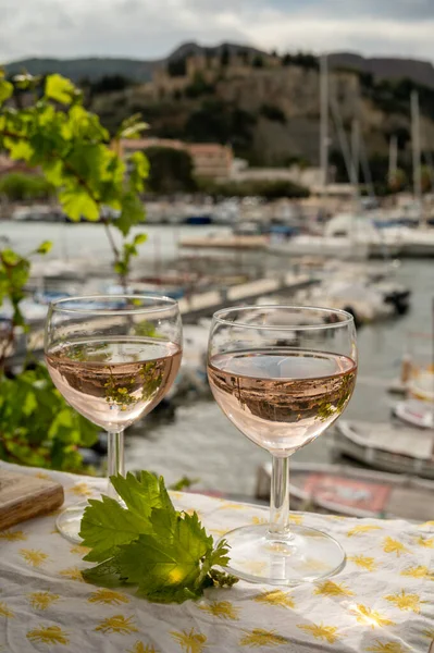 Açık terasta sunulan Rose Provencal şarabı Cassis, Provence, Fransa 'da renkli tekneleri olan eski balıkçıların limanına bakıyor.
