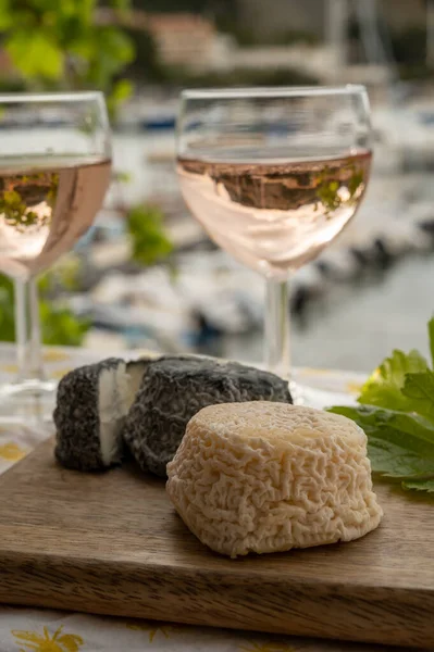 Bardakta Rose Provencal şarabı, açık terasta keçi peyniri ve Cassis, Provence, Fransa 'da renkli tekneleri olan eski balıkçıların limanına bakan manzaralı.